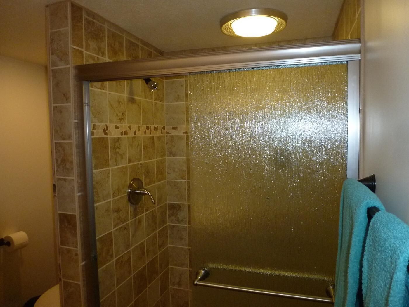 A bathroom with a glass shower enclosure, a towel rack, and a toilet.