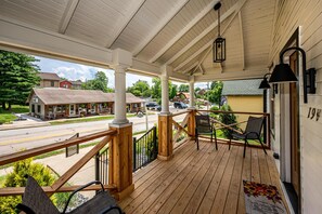 A wooden porch with a railing, a bench, and a chair.