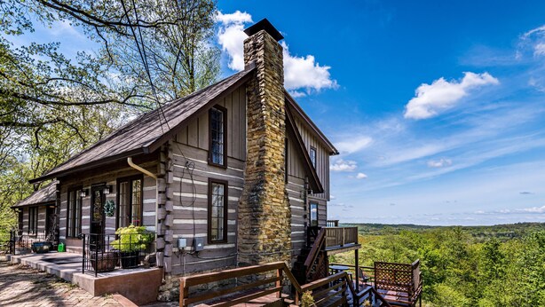 A log cabin with a stone chimney, wooden deck, and a scenic view of the forest. - Ridgetop Cabin w/ Hot Tub & Sunset Views | 2 Min to Nashville 2BR+, 2 BA (Nashville)