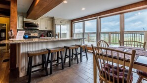 A kitchen with a large island, bar stools, and a dining area with a view. - Ridgetop Cabin w/ Hot Tub & Sunset Views | 2 Min to Nashville 2BR+, 2 BA (Nashville)