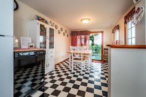 Kitchen with a checkered floor, refrigerator, dishwasher, and table with chairs, offering a convenient space for meal preparation.