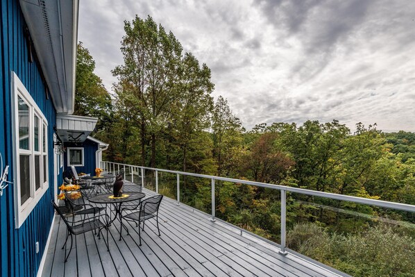 A wooden deck with outdoor furniture, a railing, and a view of a forested area.