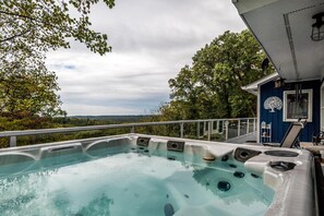 Uma banheira de hidromassagem com vista para a paisagem, um deck e um edifício azul com antena parabólica.