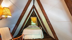 Ein gemütliches Schlafzimmer im Dachgeschoss mit Bett, Stuhl und Lampe.