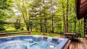 A hot tub on a wooden deck with a view of a forest. - Ridge View Log Cabin | Hot Tub, Game Shed & EV Charger 2BR, 2 BA (Nashville)