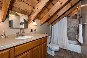 A bathroom with a wooden ceiling, a sink, a toilet, and a bathtub. - Ridge View Log Cabin | Hot Tub, Game Shed & EV Charger 2BR, 2 BA (Nashville)