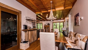 Una cocina amplia con vigas de madera, un candelabro y un comedor con sofá y sillones.