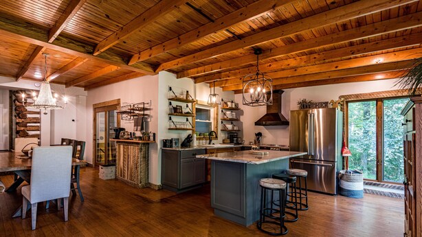 Una cocina amplia con vigas de madera, una isla central con taburetes y un refrigerador grande.