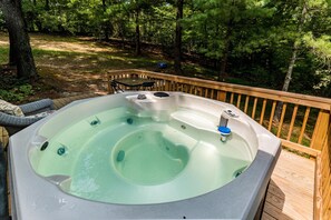 A hot tub on a wooden deck surrounded by trees.