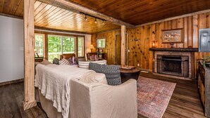 Una habitación acogedora con chimenea, paredes de madera, una cama grande y vistas al exterior.