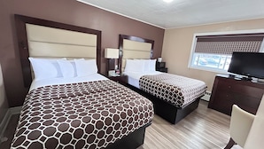 Habitación de hotel con dos camas, televisión, escritorio y ventana con vista a la calle.
