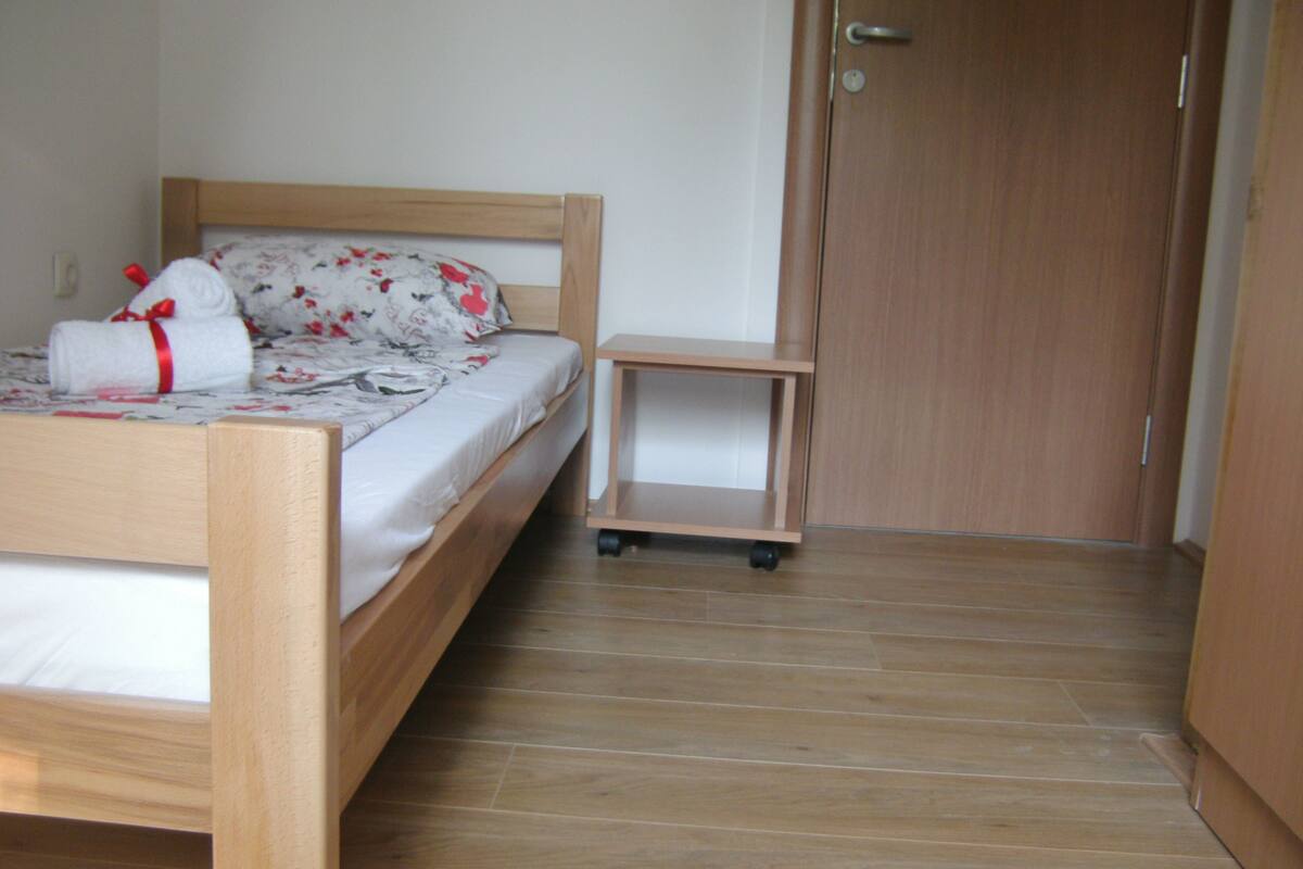 A bedroom with a wooden bed, a small bedside table, and a wardrobe.