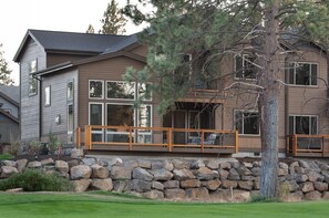A two-story house with a stone retaining wall, large windows, and a wooden deck. - Bend Milepost 1  townhome - Mt. Bachelor, bike trails, golf  (Bend)