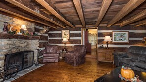 A cozy log cabin interior with a stone fireplace, leather armchairs, a sofa, and wooden beams on the ceiling. - 4 BR, 2 BA Log Cabin, charming mix of old and new, close to village of Story (Nashville)