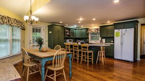 A kitchen with wooden cabinets, a dining table, and chairs. - 4 BR, 2 BA Log Cabin, charming mix of old and new, close to village of Story (Nashville)