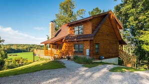 A log cabin with a porch, a chimney, and a gravel driveway. - View Cabin w/ Hot Tub, Pond & Pool Table | Secluded Retreat 3BR, 2BA (Nashville)