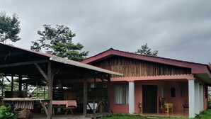 Ein rustikales Haus mit überdachter Veranda, Essbereich und kleinem Garten.