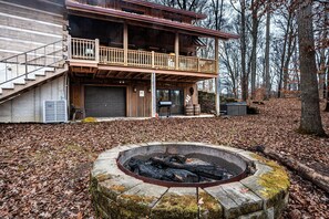 A cabin with a deck, a fire pit, and a garage.