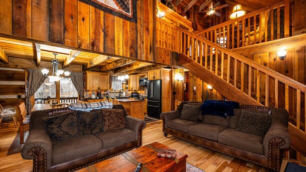 Un intérieur rustique en bois, avec un escalier, des meubles en bois et un coin cuisine.