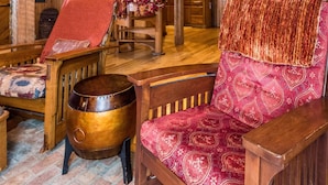 Un interno rustico in legno con soffitto alto, una scala e un'accogliente area salotto con una poltrona a motivi e un tavolino.