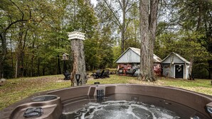 Jacuzzi envoltat d'arbres, amb un pont de fusta i una cabana rústica.
