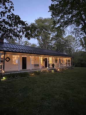 A house with a porch, a black door, and a garden.