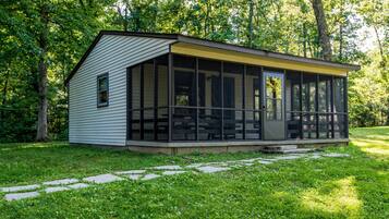 Situated among lush greenery, this cabin-style building offers a covered porch for relaxation.