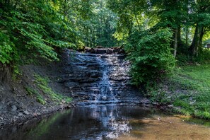 A waterfall cascading into a calm river surrounded by dense greenery. - 2BR, 1BA cottage (Norman)