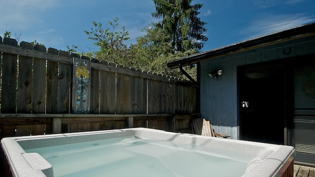 A hot tub in a backyard with a wooden fence and a building in the background. - In Town Nashville Stay | Hot Tub & Walk Everywhere 1BR, 1BA (Nashville)