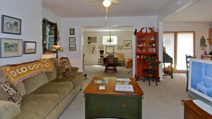 A living room with a sofa, coffee table, and a television. There is a dining area with a table and chairs in the background. - In Town Nashville Stay | Hot Tub & Walk Everywhere 1BR, 1BA (Nashville)