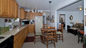 A kitchen with wooden cabinets, a dining table with chairs, a refrigerator, and a chandelier. - In Town Nashville Stay | Hot Tub & Walk Everywhere 1BR, 1BA (Nashville)