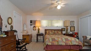 A bedroom with a bed, dresser, chair, bedside tables, lamps, and a ceiling fan. - In Town Nashville Stay | Hot Tub & Walk Everywhere 1BR, 1BA (Nashville)