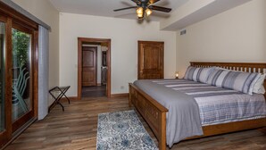A bedroom with a wooden bed, a ceiling fan, and a view through a glass door to the outside. - 100-Acre Private Cabin | Trails, Creek, Pond & Total Seclusion 4BR, 4BA (Nashville)