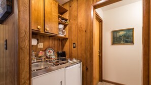 Eine kleine Küche mit Holzausstattung, einem Spülbecken und einem Kühlschrank.
