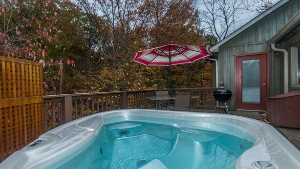 A hot tub with a wooden deck and a patio umbrella. - Romantic Cottage for Two | Hot Tub, Fireplace & Near Nashville 1 BR, 1BA (Morgantown)