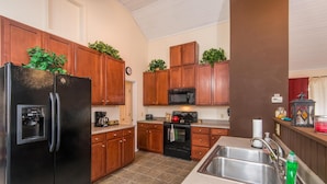 A kitchen with wooden cabinets, a black refrigerator, a microwave, and a stainless steel sink. - Romantic Cottage for Two | Hot Tub, Fireplace & Near Nashville 1 BR, 1BA (Morgantown)