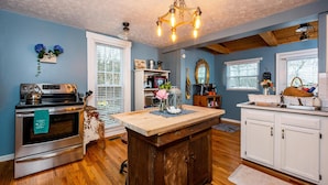 A kitchen with a wooden island, stainless steel appliances, and a chandelier.