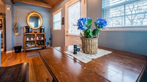A wooden dining table with a woven basket containing blue flowers, a coffee maker, and a salt shaker.
