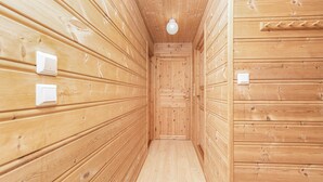 Interior em madeira com porta central, interruptores de luz e luminária no teto.