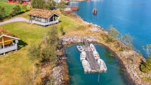 Uma propriedade à beira do lago com um cais, barcos e uma casa com terraço.