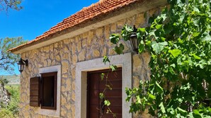 Un bâtiment en pierre avec un toit en tuiles, une porte en bois et une fenêtre avec des volets.