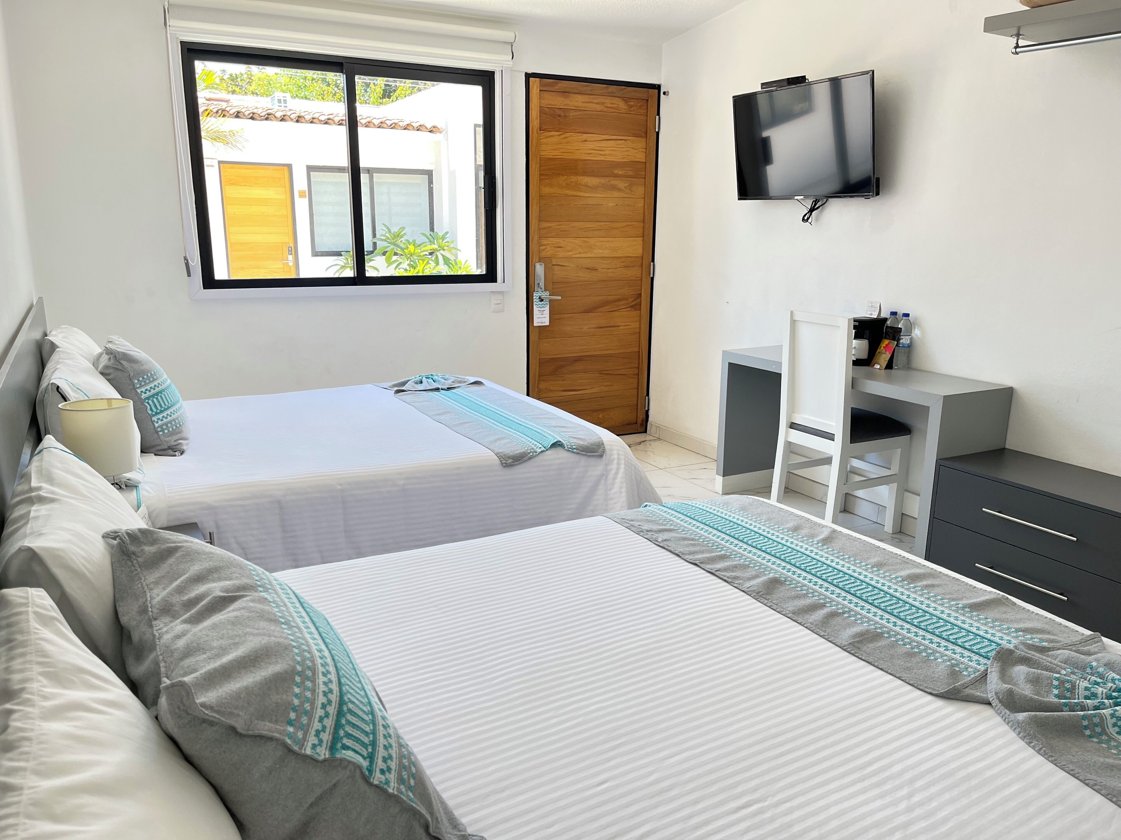 Een hotelkamer met twee bedden, een televisie, een bureau en een kledingkast.
