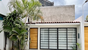 Ein modernes Haus mit einem großen Schiebeglasfenster, einer Holztür und einer kleinen Veranda.