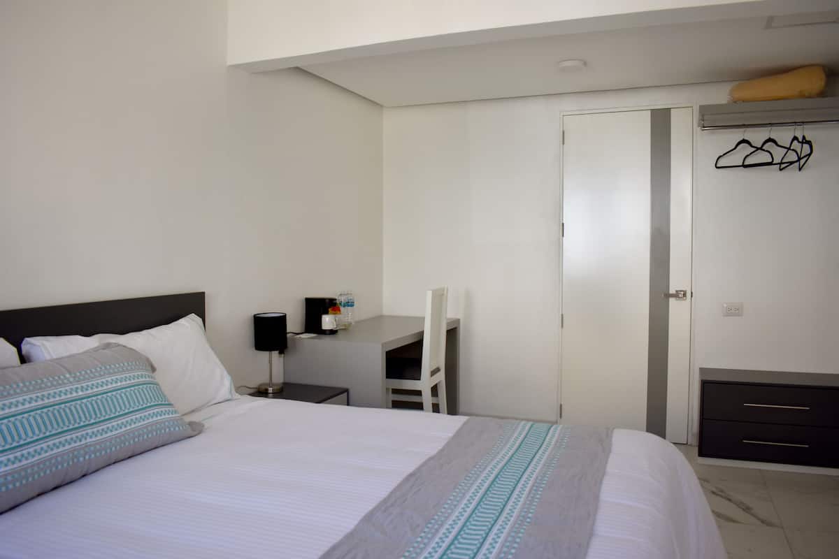 Une chambre d’hôtel comprenant un lit, un bureau, une chaise et une armoire.