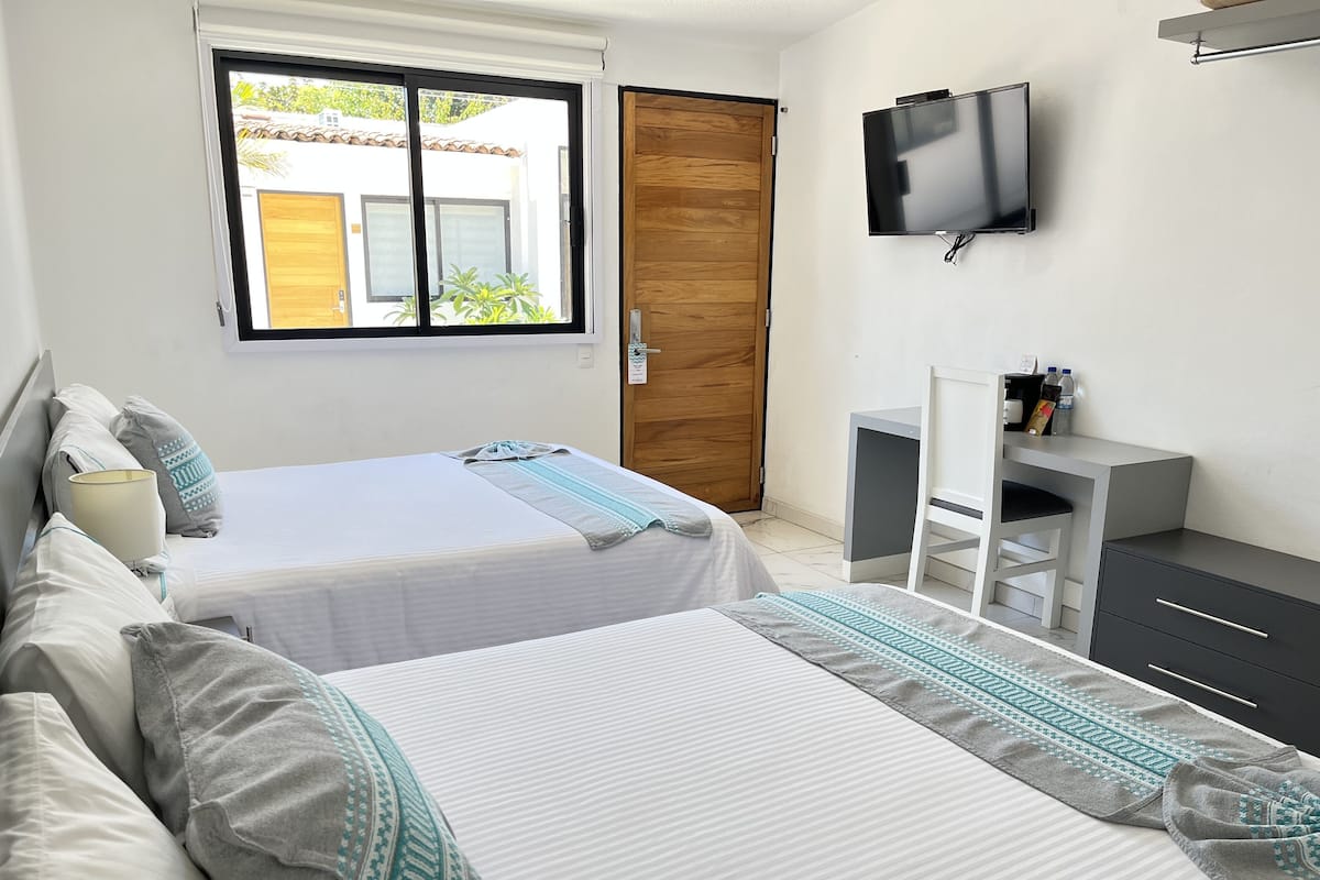 Une chambre d’hôtel avec deux lits, une télévision, un bureau et une armoire.