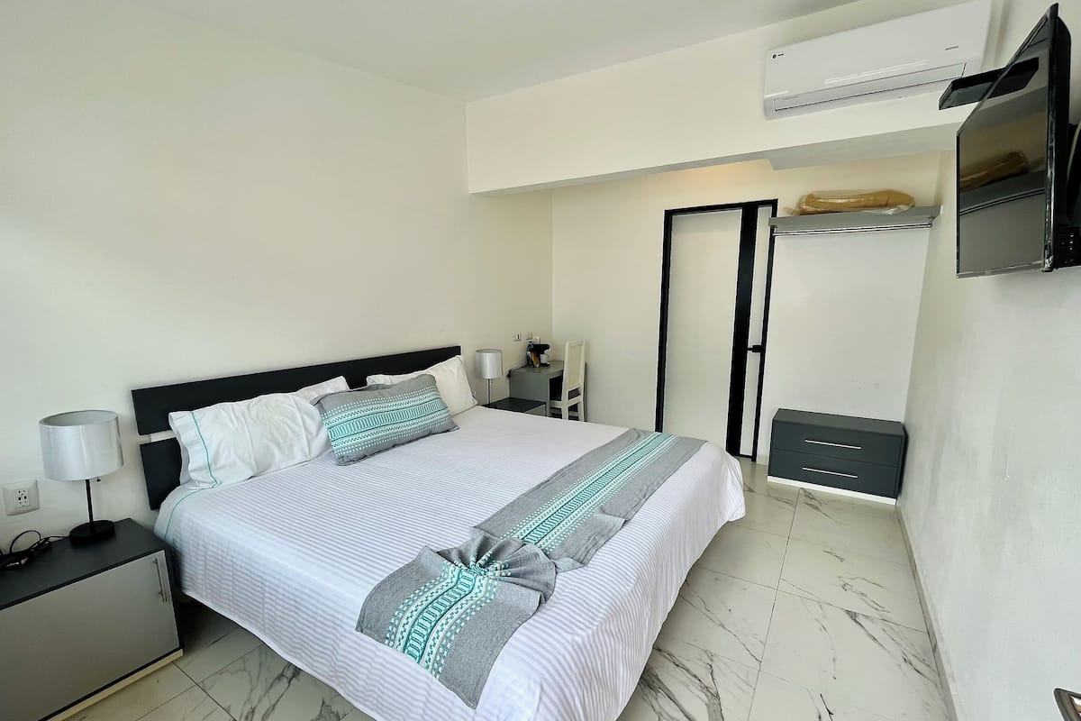Une chambre bien rangée, avec un lit, des tables de chevet, un bureau, un appareil de climatisation et une armoire.
