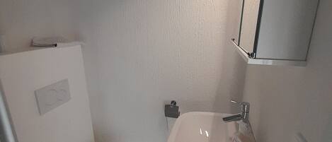 Ein kleines, kompaktes Badezimmer mit Toilette, Waschbecken und einem Spiegel darüber.