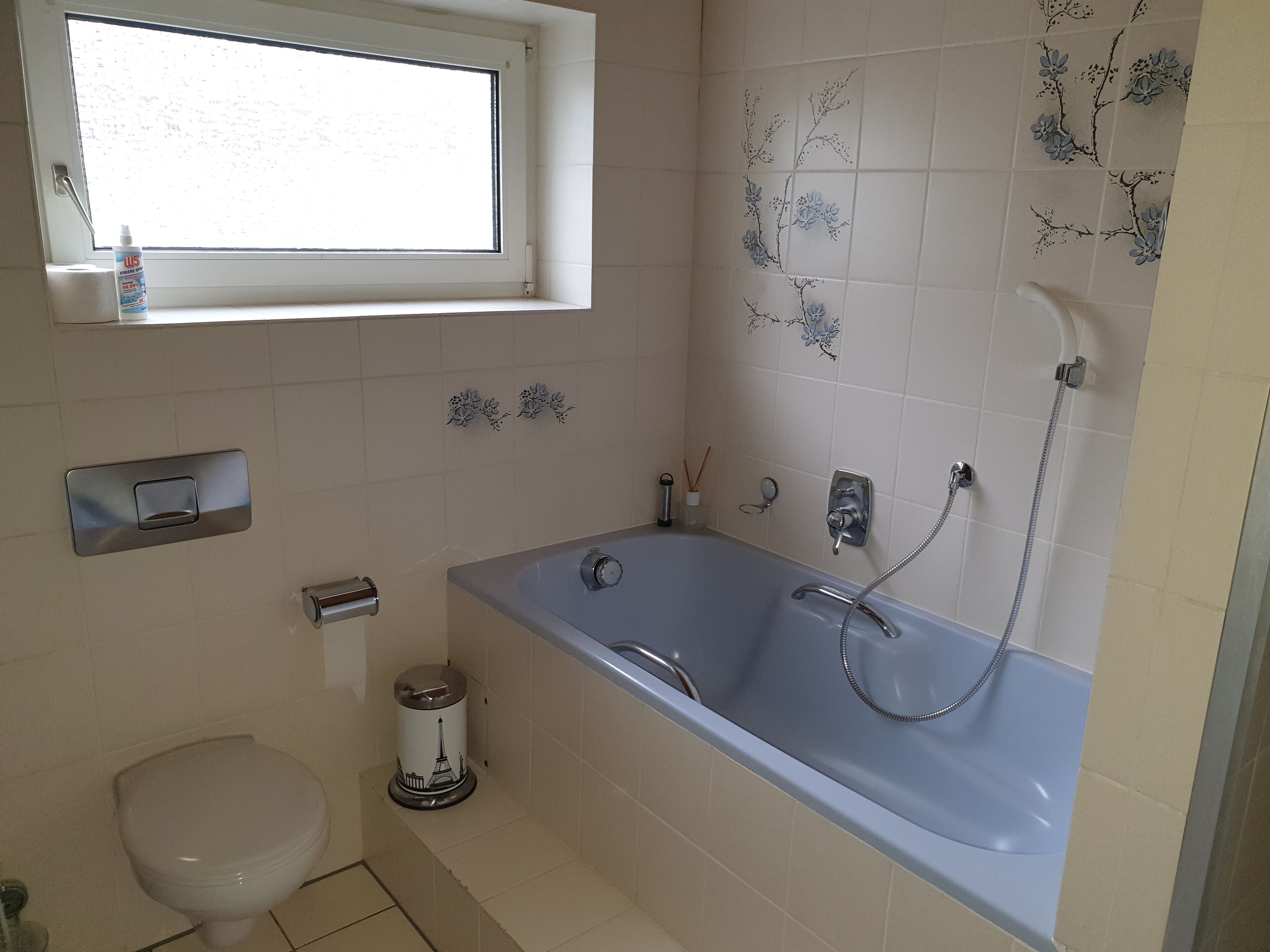 Une salle de bain avec une baignoire, des toilettes et une fenêtre.