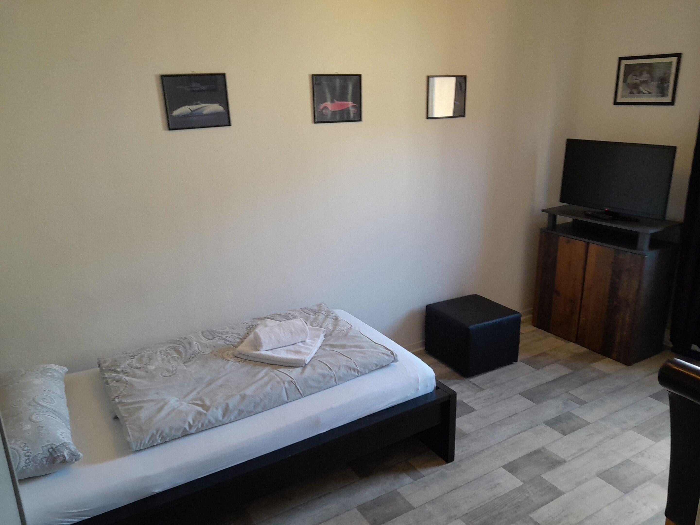 A bedroom with a bed, a TV, and a small wooden cabinet.