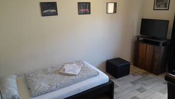 A bedroom with a bed, a TV, and a small wooden cabinet.
